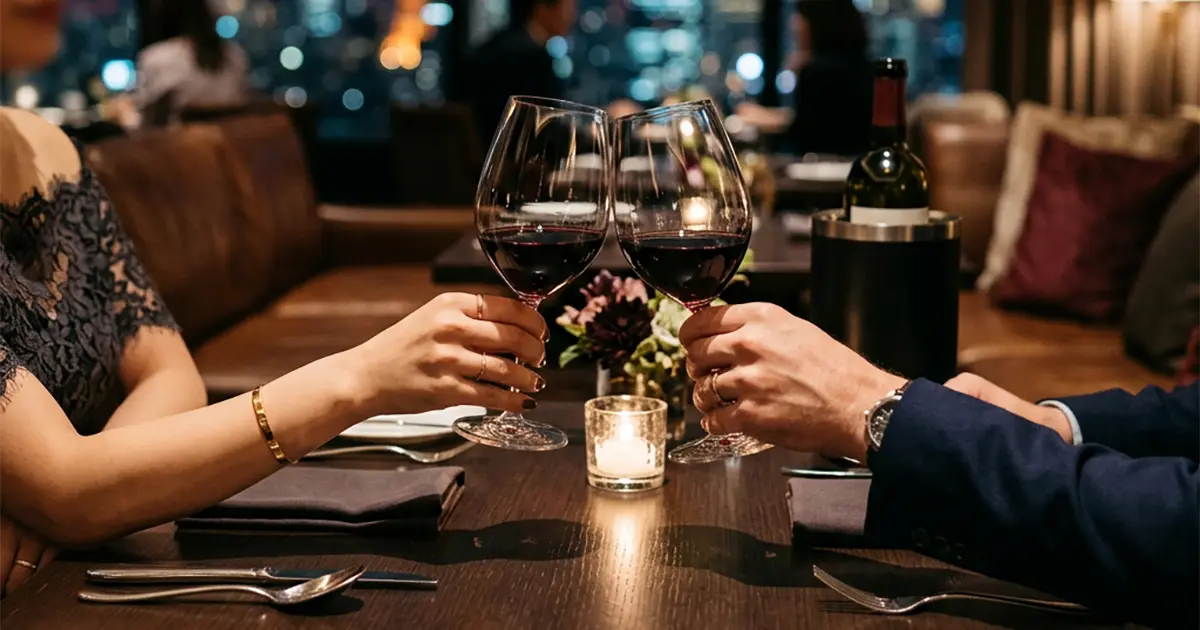 Two hands and wine glasses across a dinner table
