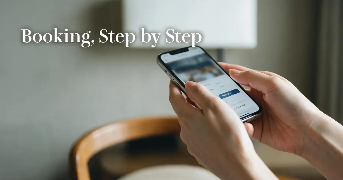 Woman's hands holding a smartphone with an English booking page open in a softly lit Tokyo hotel room