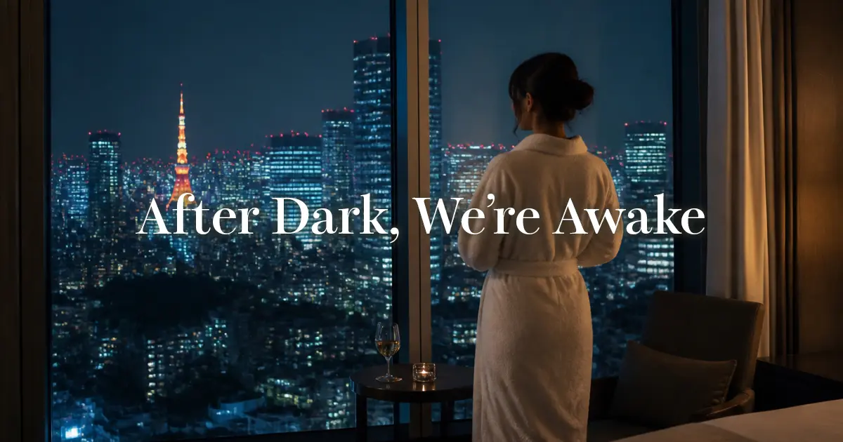 Woman in a robe looking out at the Tokyo skyline from her hotel room at night