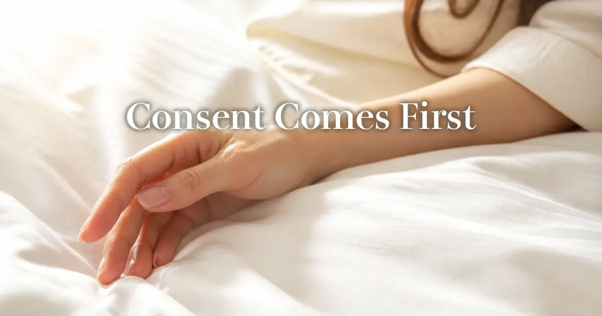 Relaxed woman’s hand resting on white hotel sheets in soft warm light