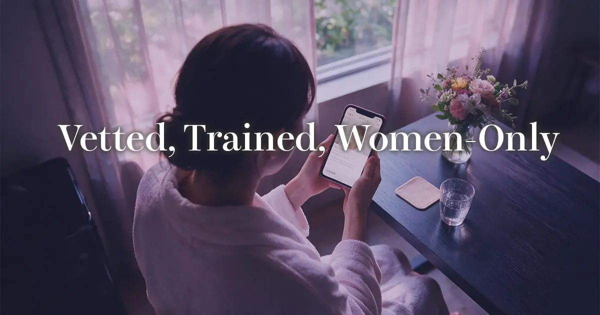 Woman in a bathrobe browsing therapist profiles on her phone, seen from behind